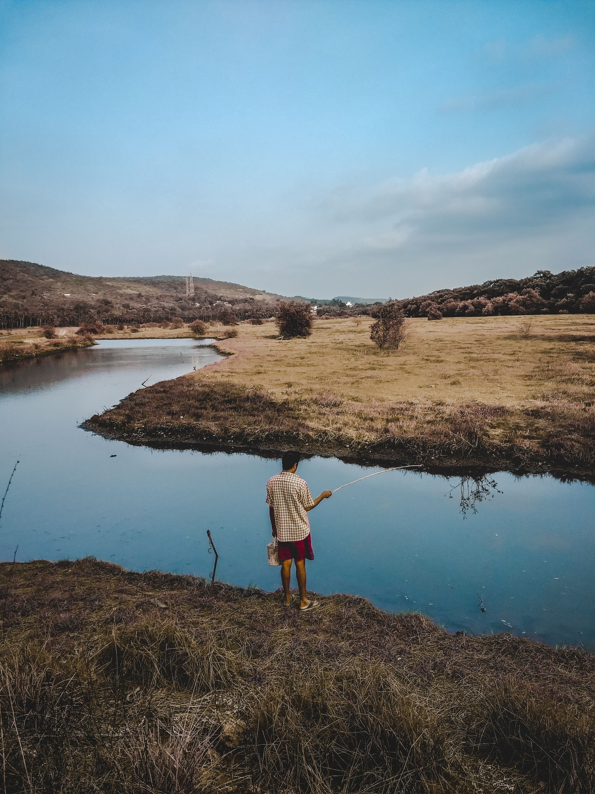 A fisherman beside a quiet country river